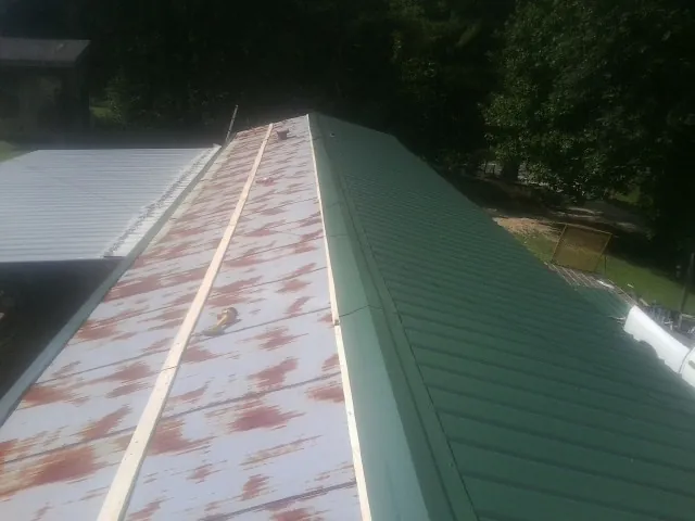 Old rusted panels beside newly installed green metal roofing — Wind Damage Roof Repair by Roofing Brothers in Felt