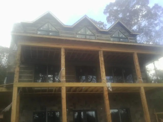 Dormers and porch framing on a large log home under construction — Roof Coating work by our crew in Felt