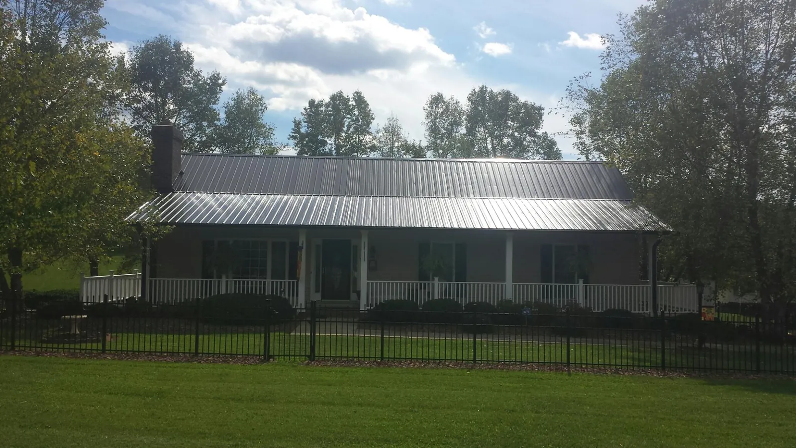 Gray metal roof on a brick ranch with a full width front porch — Gutter Guard Installation work by our crew in Felt